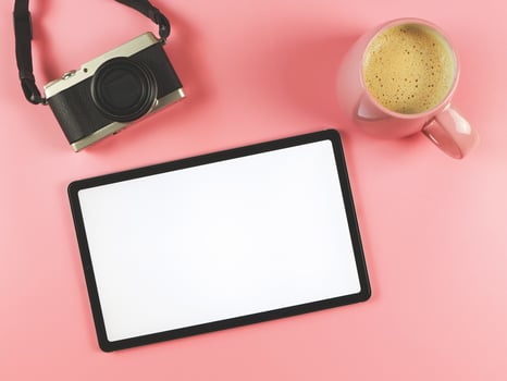 flat lay of digital tablet with blank white screen , digital camera and pink cup of coffee isolated on pink background. photo