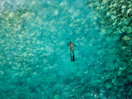 Aerial drone view of a person doing spearfishing on crystal blue water. Recreational fishing and summer activity. Summertime. photo