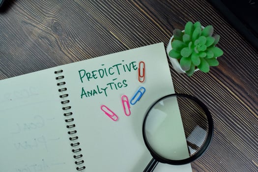 Predictive Analytics write on a book isolated on Wooden Table. photo