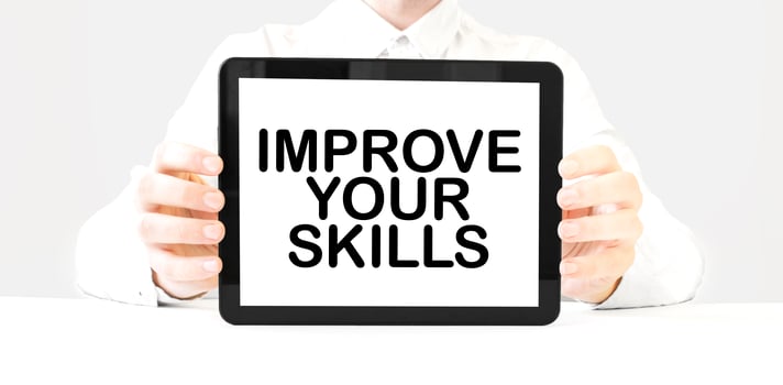 Text IMPROVE YOUR SKILLS on tablet display in businessman hands on the white background. Business concept photo