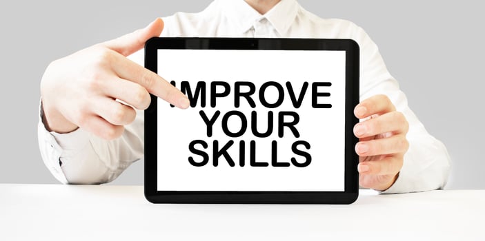 Text IMPROVE YOUR SKILLS on tablet display in businessman hands on the white background. Business concept photo