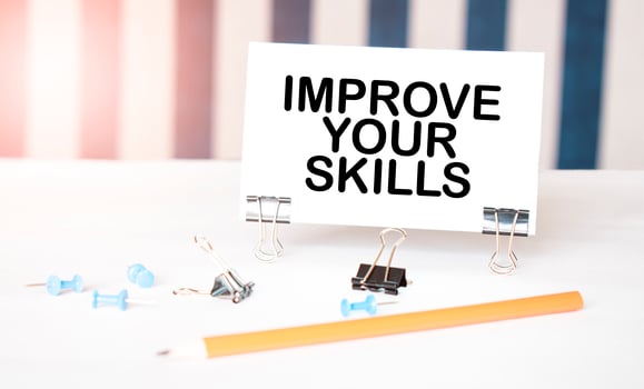 IMPROVE YOUR SKILLS sign on paper on white desk with office tools. Blue and white background photo