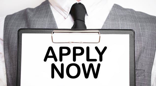 Businessman holding sheet of paper with a message APPLY NOW photo