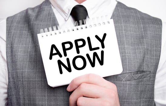 Businessman with notebook with text APPLY NOW photo