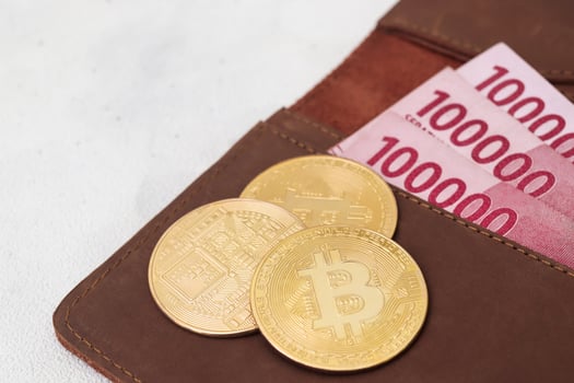 Bitcoin with one hundred thousand rupiah banknote on leather wallet. Cryptocurrency trading concept photo