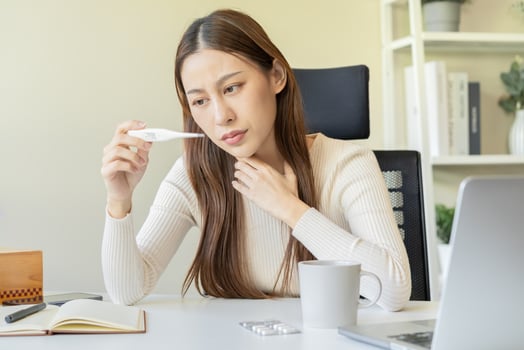 Sick, influenza asian young woman, girl headache have a fever, flu and check thermometer measure body temperature, feel illness while sitting work at home, office. Health care, infection of covid-19 photo