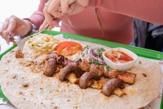 Woman eating grilled kebab with pita bread and vegetables on tray in summer fast food street cafe photo