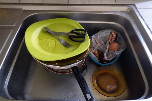 Dishwashing with piles of dirty dishes and food waste photo