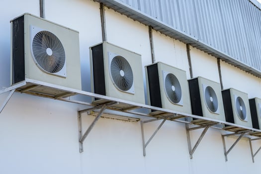 Several air compressors absorb heat circulating air attached to a white wall flap. photo