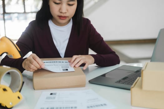 Young business owner putting shipping label on parcel. photo