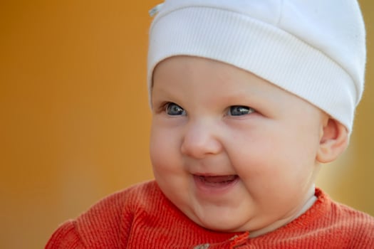 The face of a six-month-old cheerful baby. Happy baby in a hat. photo