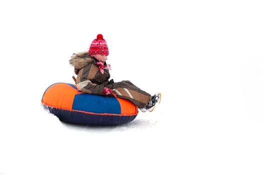 Child in winter. Cheerful boy is riding an inflatable sled. photo