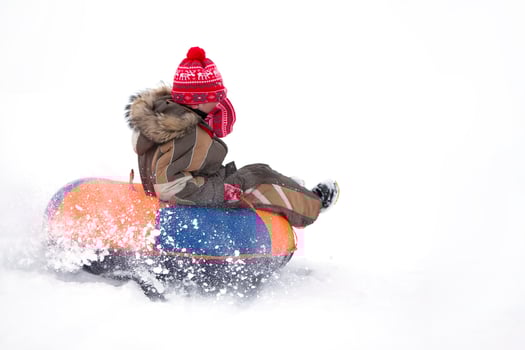 Child in winter. Cheerful boy is riding an inflatable sled. photo