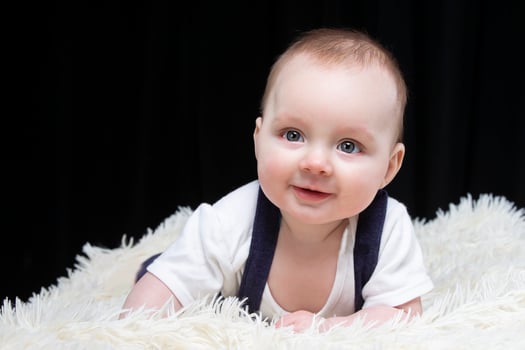 Beautiful baby boy smiles and looks into the camera. Baby at four months old. A funny child. photo
