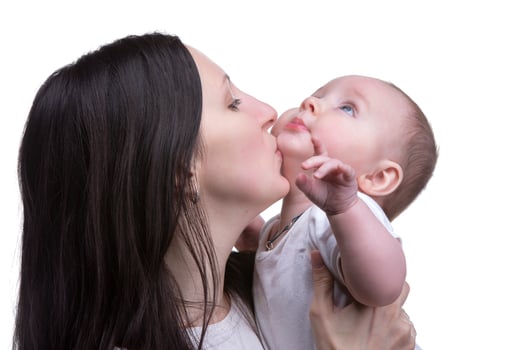 Mom kisses her little son on a light background. Motherhood. photo