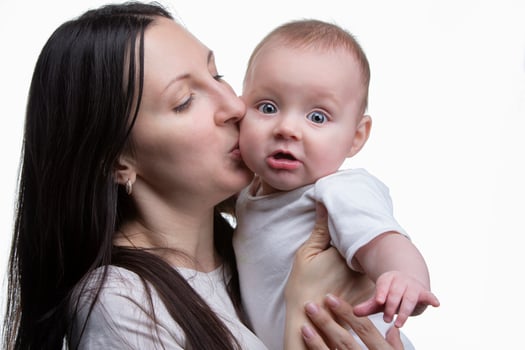 Mom kisses her little son on a light background. Motherhood. photo
