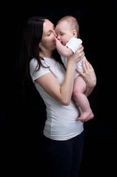 Beautiful mother hugs her baby. Motherhood.Mom and little son on a dark background. Motherhood. photo