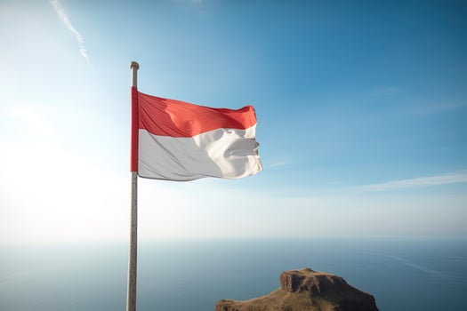 Indonesia national flag waving in the blue sky on the ocean background. Red and white flag with clouds. photo