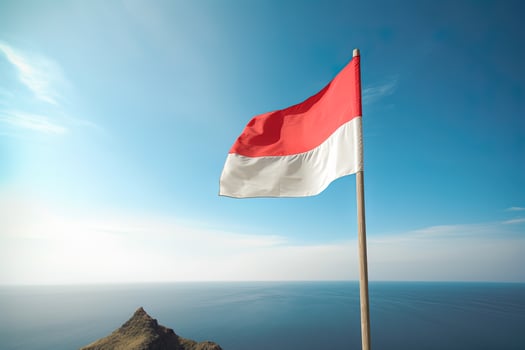 Indonesia national flag waving in the blue sky on the ocean background. Red and white flag with clouds. photo