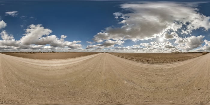 spherical 360 hdri panorama on gravel road with clouds and sun on blue sky in equirectangular seamless projection, use as sky replacement in drone panoramas, game development as sky dome or VR content photo