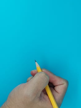 The hand holds an acutely sharpened pencil photo