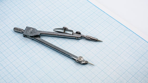 Drawing compass isolated on graph paper photo