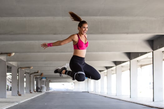Fitness woman jumping outdoor in urban environment. Active woman being full of energy, jumps high in air, prepares for sport competitions. . Gymnastics concept photo