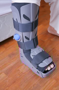 women broken feet with a grey plastic boot ankle brace injury protecting boot photo