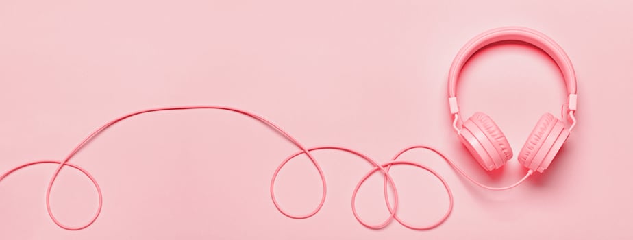 Pink headphones on pink banner. Minimal Music concept, flat lay, copy space, monochrome colors photo