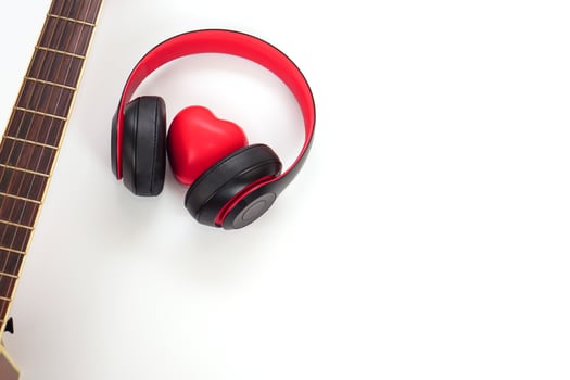 Acoustic guitar, headphones and red heart on a white background. Love, entertainment and music concept. photo