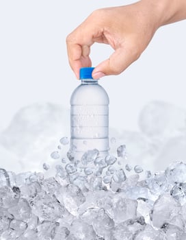 A man hand with bottle of water passing through ice cubes photo