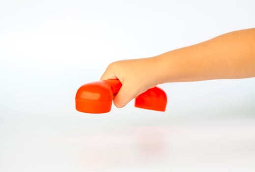 Red toy phone in the child's hand. Close-up of a child's hand. Isolated on a white background. The concept of an advertising banner. photo