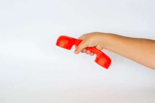 Red toy phone in the child's hand. Close-up of a child's hand. Isolated on a white background. The concept of an advertising banner. photo