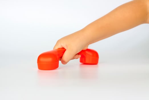 Red toy phone in the child's hand. Close-up of a child's hand. Isolated on a white background. The concept of an advertising banner. photo
