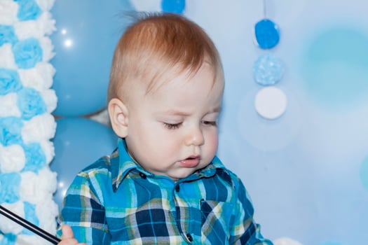A beautiful baby is celebrating his first birthday. Portrait of the baby. A boy in a blue shirt among balloons and gifts. photo