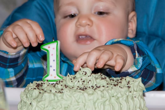 A beautiful baby celebrates his first birthday and eats a cake with his hand. Cake with the number one on the table in front of the child. photo