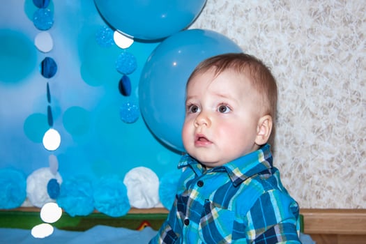 A beautiful baby is celebrating his first birthday. Portrait of the baby. A boy in a blue shirt among balloons and gifts. photo