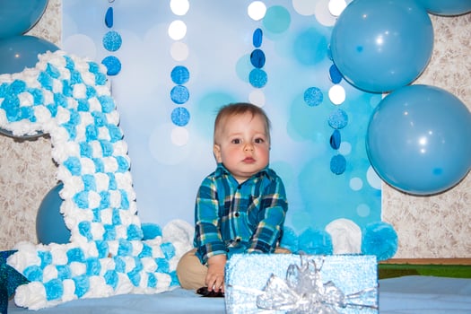 A beautiful baby is celebrating his first birthday. Portrait of the baby. A boy in a blue shirt among balloons and gifts. photo