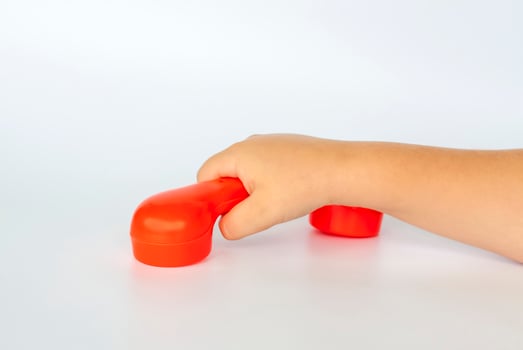 Red toy phone in the child's hand. Close-up of a child's hand. Isolated on a white background. The concept of an advertising banner. photo