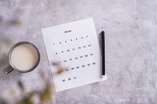 Calendar sheet for planning and a cup of coffee with milk on the table top view photo