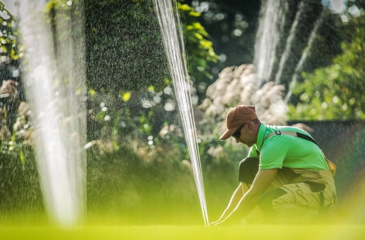 Worker Adjusting Water Sprinkler photo