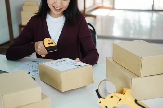 Female online business owner scan shipping label on parcel. photo