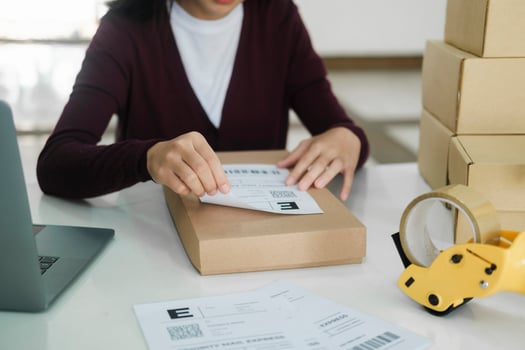 Young business owner putting shipping label on parcel. photo
