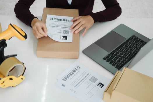 Young business owner putting shipping label on parcel. photo