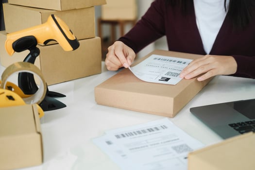 Young business owner putting shipping label on parcel. photo