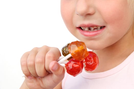 Child eats candy. Girl has caries on teeth. photo