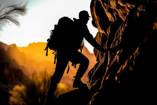 male climber climbing mountains dark silhouette against the background of the sun photo