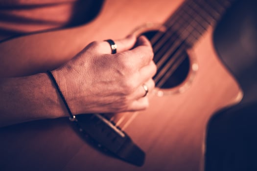 Male Musician Playing On Acoustic Guitar While Sitting Down. photo