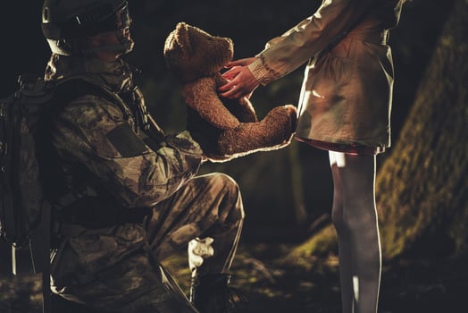Soldier Giving Teddy Bear Toy to Caucasian Girl photo