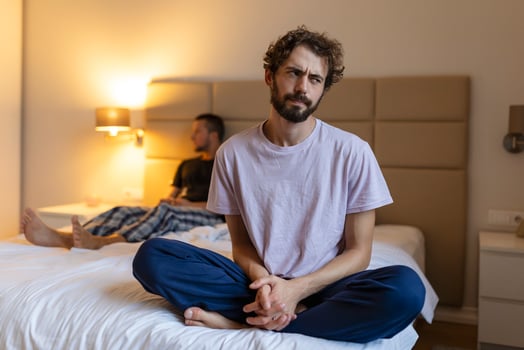 Frustrated sad boyfriend sit on bed think of relationship problems, thoughtful gay couple after quarrel lost in thoughts, upset lovers consider break up, offended person disappointed by boyfriend photo